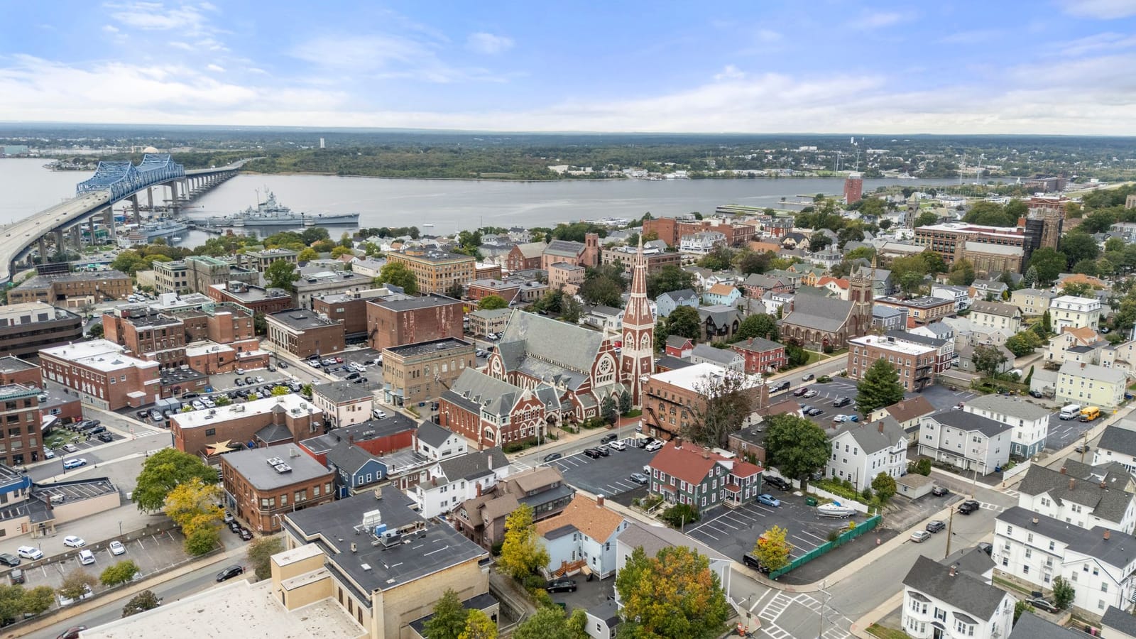 Aerial view over downtown Fall River toward the Taunton River, the Braga Bridge, and Battleship Cove